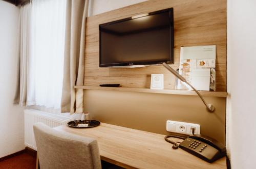 a room with a desk with a television and a telephone at Hotel Frauensteiner Hof in Frauenstein