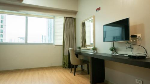 a room with a desk with a flat screen tv at Avant Serviced Suites - Personal Concierge in Manila