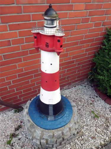 a red and white lighthouse sitting next to a brick wall at Pension Stürrad in Neuharlingersiel