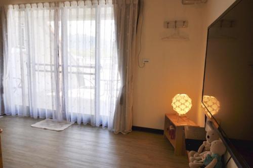 a room with a large window with white curtains at Village Villa B&B in Zhuqi
