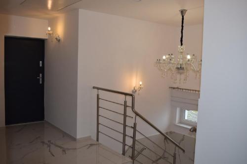 a hallway with a black door and a chandelier at Sunrise Apartaments in Rowy