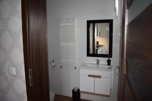 a white bathroom with a sink and a mirror at Sunrise Apartaments in Rowy