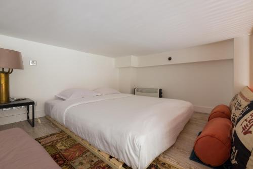 a bedroom with a large white bed and a couch at Veeve - Natural Heights in the 6th in Paris