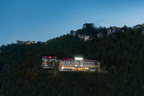 a building on top of a hill with lights on at 8fold by LaRiSa in Shimla