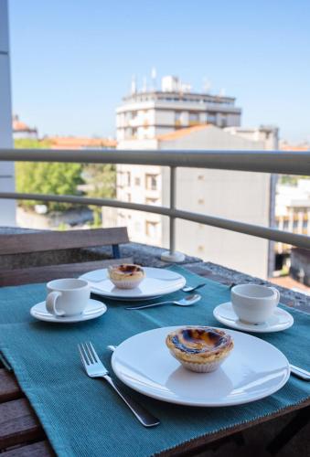 a table with cups and saucers on top of a balcony at Porto Gaia River View 8 by MP in Vila Nova de Gaia