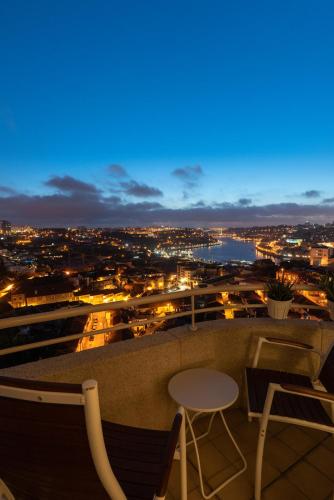 a view of a city at night with a table and chairs at Porto Gaia River View 8 by MP in Vila Nova de Gaia