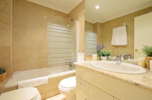 a bathroom with a toilet and a sink and a tub at City Center Apartment in Valencia