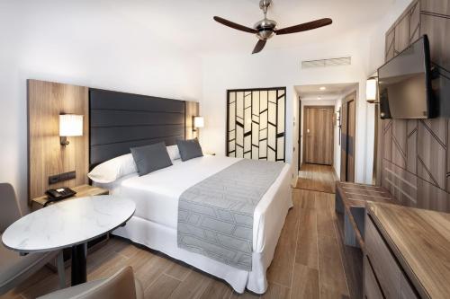 a bedroom with a large white bed and a table at Hotel Riu Palace Oasis in Maspalomas