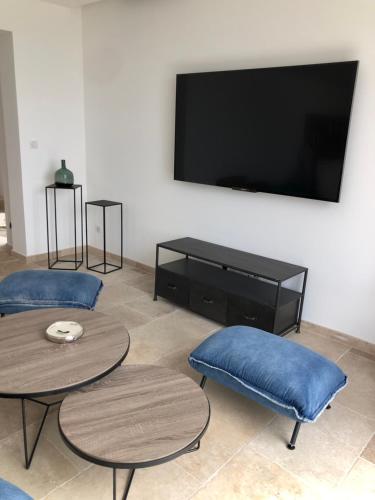 a living room with two tables and a flat screen tv at LA POINTE D’ASPRETTO in Ajaccio