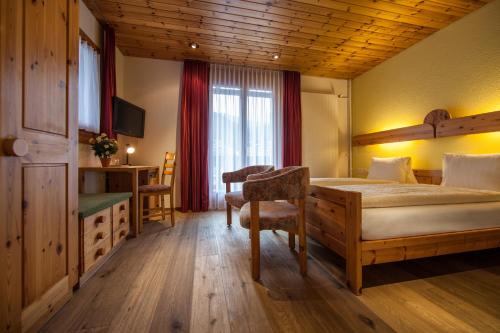 a bedroom with a bed and a desk and a window at Hotel Astoria in Arosa