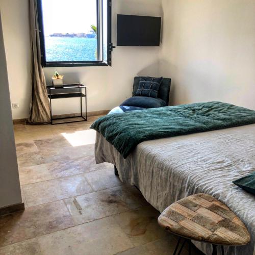 a bedroom with a bed and a chair and a window at LA POINTE D’ASPRETTO in Ajaccio