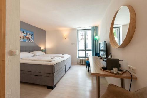 a bedroom with a bed and a desk and a mirror at Hotel Am Dom in Bamberg