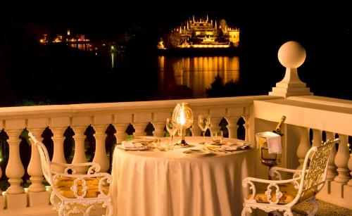 a table and chairs on a balcony at night at Grand Hotel Bristol in Stresa
