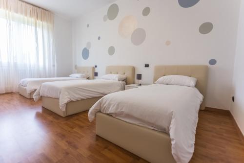 2 camas en un dormitorio con paredes blancas y suelo de madera en LM House, en Lonato