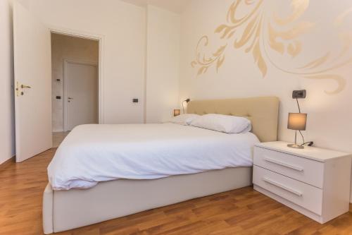 a white bedroom with a white bed and a nightstand at LM House in Lonato del Garda