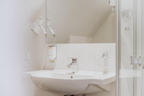 a white bathroom with a sink and a shower at Hotel Frauensteiner Hof in Frauenstein