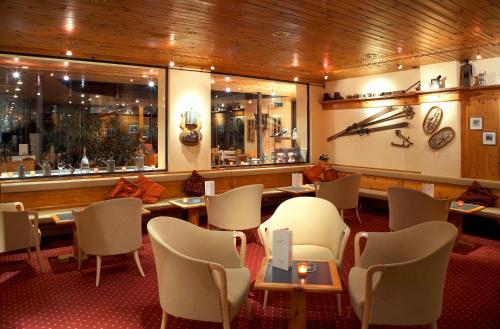 a restaurant with white chairs and tables and windows at Hotel Astoria in Arosa