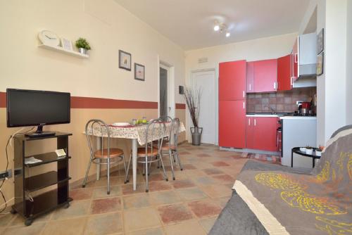 a living room with a table and a kitchen with red cabinets at LA DIGA - Bilocale a Marzamemi, fronte mare in Marzamemi