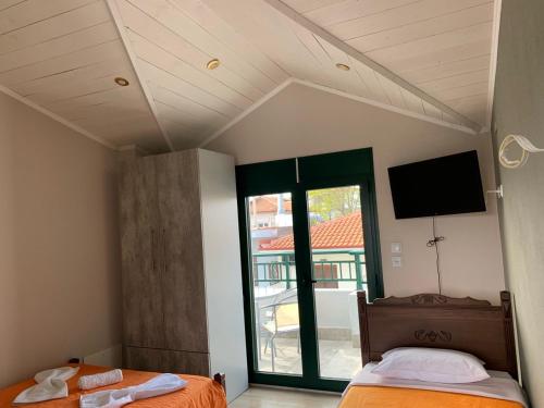 a bedroom with two beds and a flat screen tv at Studio Theano in Kallithea Halkidikis