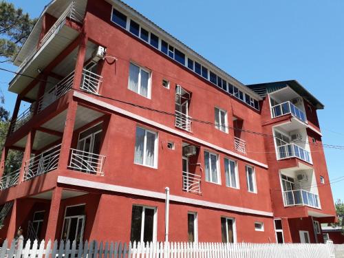 a red building with a white fence in front of it at New Wave1 in Grigoleti