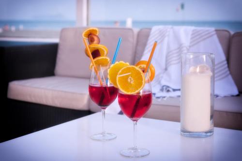 two glasses of red wine and orange slices on a table at Hotel Mediterraneo in Lido di Latina 