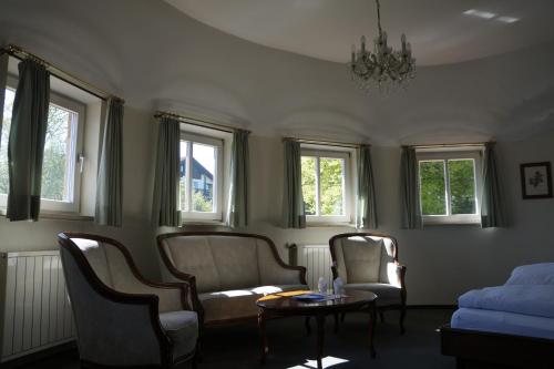 a living room with chairs and a table and windows at Villa am Park in Bad Tölz