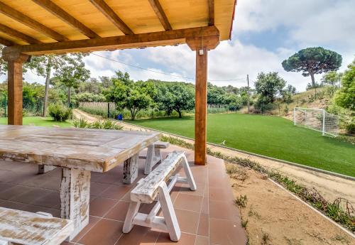 a wooden picnic table and bench under a wooden pergola at Vivalidays Can Palomo in Palafolls