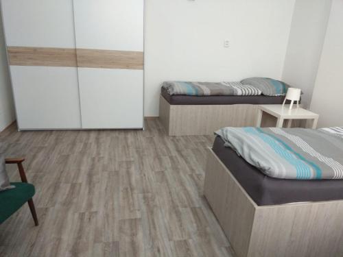 two beds in a room with wooden floors at Apartmány U splavu in Veselí nad Moravou