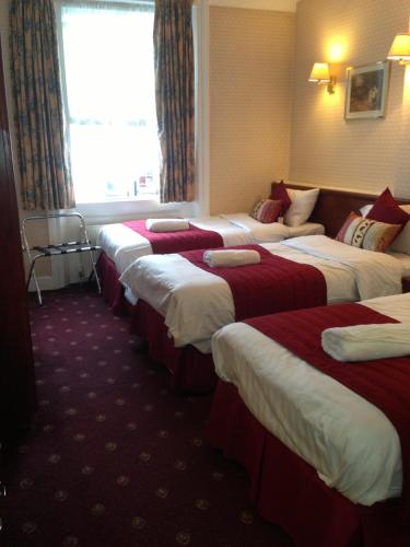 a row of beds in a hotel room at Avon Hotel in London