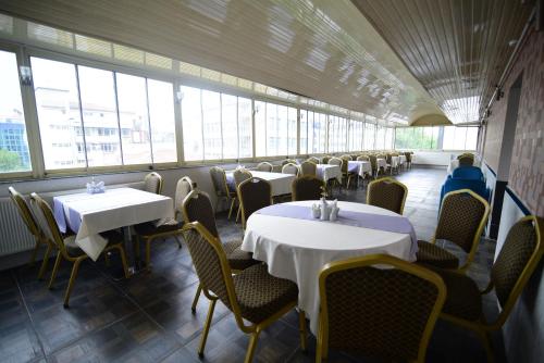 una sala da pranzo con tavoli, sedie e finestre di Özdemir Palas a Ankara