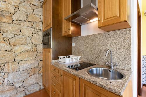 a kitchen with a sink and a stone wall at Quinta do Rio Homem in Caldelas
