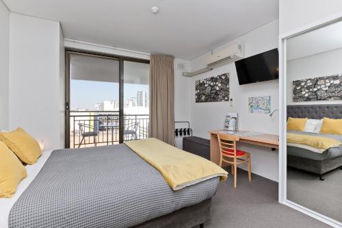 パースにあるCentral City Exclusive Apartmentsのベッド、デスク、ベッド、窓が備わるホテルルームです。