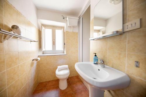 uma casa de banho com um lavatório branco e um WC. em Blue Coral Apartment em Cefalù