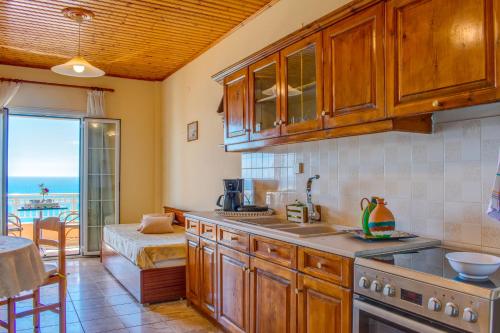 a kitchen with wooden cabinets and a view of the ocean at Naftis Apartments in Pelekas