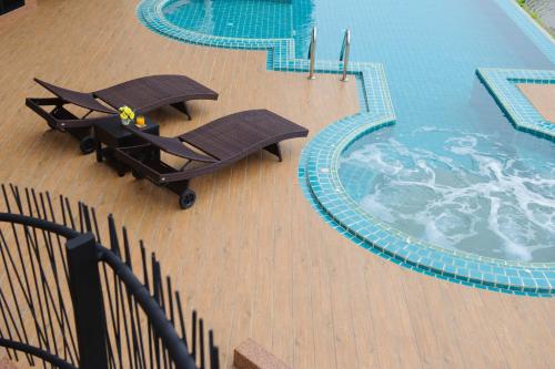 a pool with two lounge chairs next to a swimming pool at Coco View Hotel in Samut Songkhram