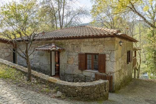 a small stone house with a stone wall around it at Quinta do Rio Homem in Caldelas