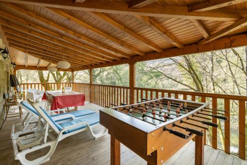 a screened in porch with a pool table and chairs at Quinta do Rio Homem in Caldelas