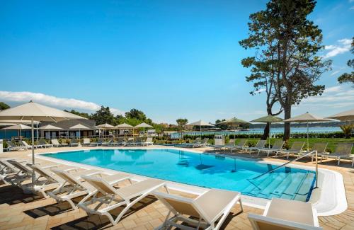 una gran piscina con sillas y sombrillas en Padova Premium Camping Resort by Valamar en Rab