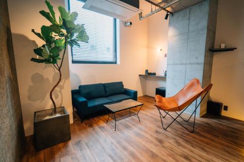 a living room with a blue couch and a plant at ZONK HOTEL Nakasu-Deaibashi in Fukuoka