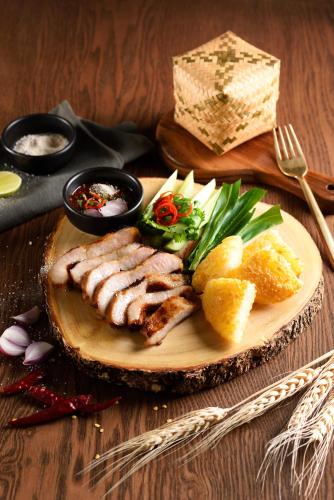 a plate of food with meat and vegetables on a table at Mayson Place Hotel in Ban Phraek Sa