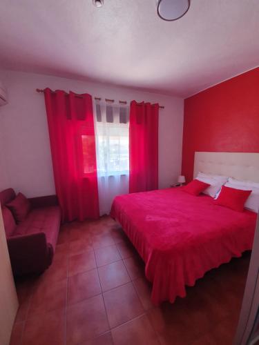 Un dormitorio rojo con una cama grande y una ventana en A Toca Do Grilo, en Carvalhal