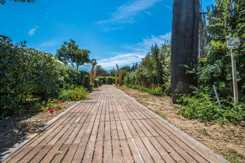 an empty wooden walkway in a garden at B&B Le Dune - Self Check in in Lascari