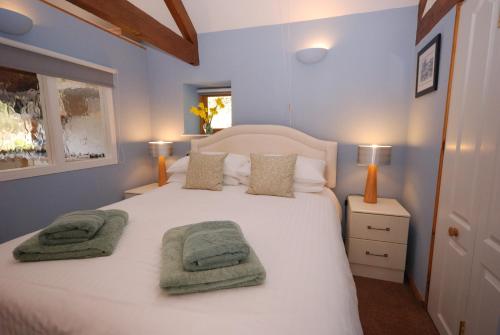 a bedroom with a white bed with two towels on it at Bowgie at Trewerry Cottages - Away from it all, close to everywhere in Newquay