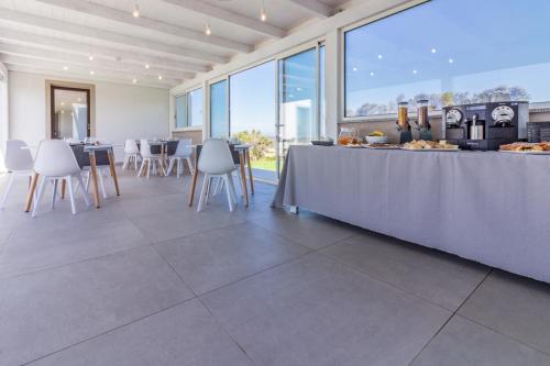 een kamer met een tafel met witte stoelen en een toonbank bij B&B Naracheddu Elite in Santa Teresa Gallura