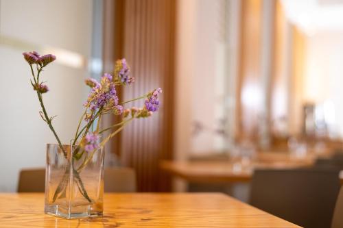 a vase filled with purple flowers sitting on a table at Vrachia Beach Hotel & Suites - Adults Only in Paphos City