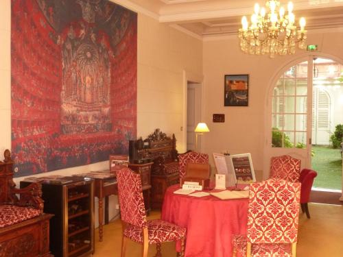 a room with a table and chairs and a large rug at Hôtel du Fiacre in Carpentras