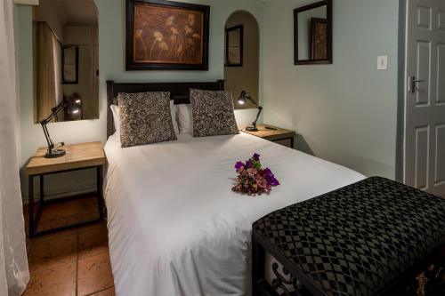 een slaapkamer met een groot wit bed met bloemen erop bij Izimbali Lodge and Restaurant in Ermelo