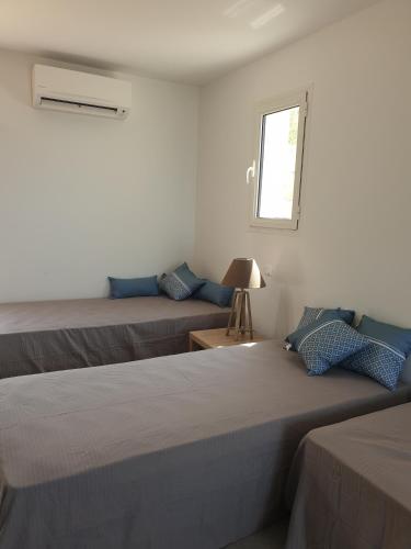 deux lits dans une chambre blanche avec une fenêtre dans l'établissement Corsica Résidence Galitello, à Monticello