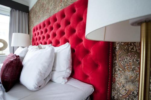 a bedroom with a red headboard and a bed with pillows at Centric Hotel in Norrköping