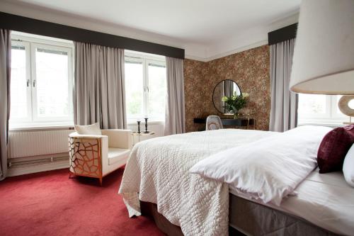 a bedroom with a bed and a chair and windows at Centric Hotel in Norrköping